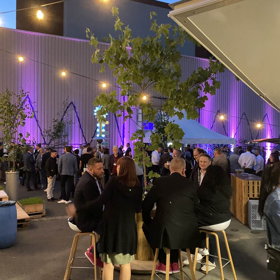 Abendveranstaltung im Hof der Spinnerei mit Lichterketten und Bäumen vor der beleuchteten Hallenfassade