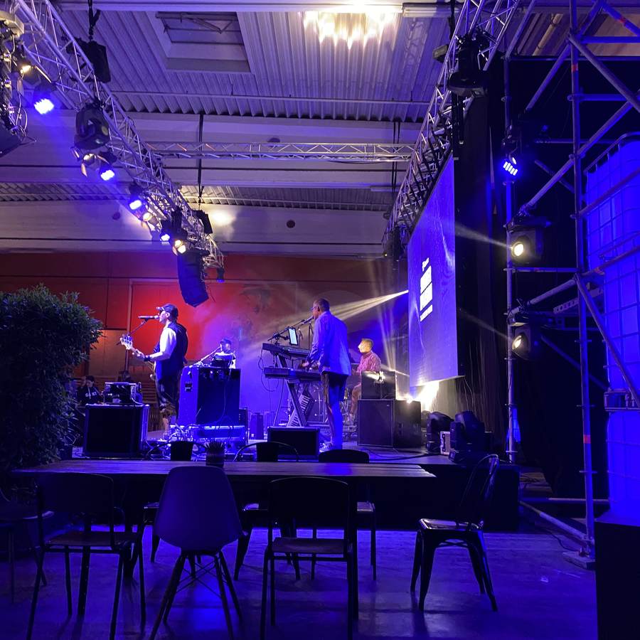 Band auf der Bühne in der Halle mit Lichttraversen und LED-Wand