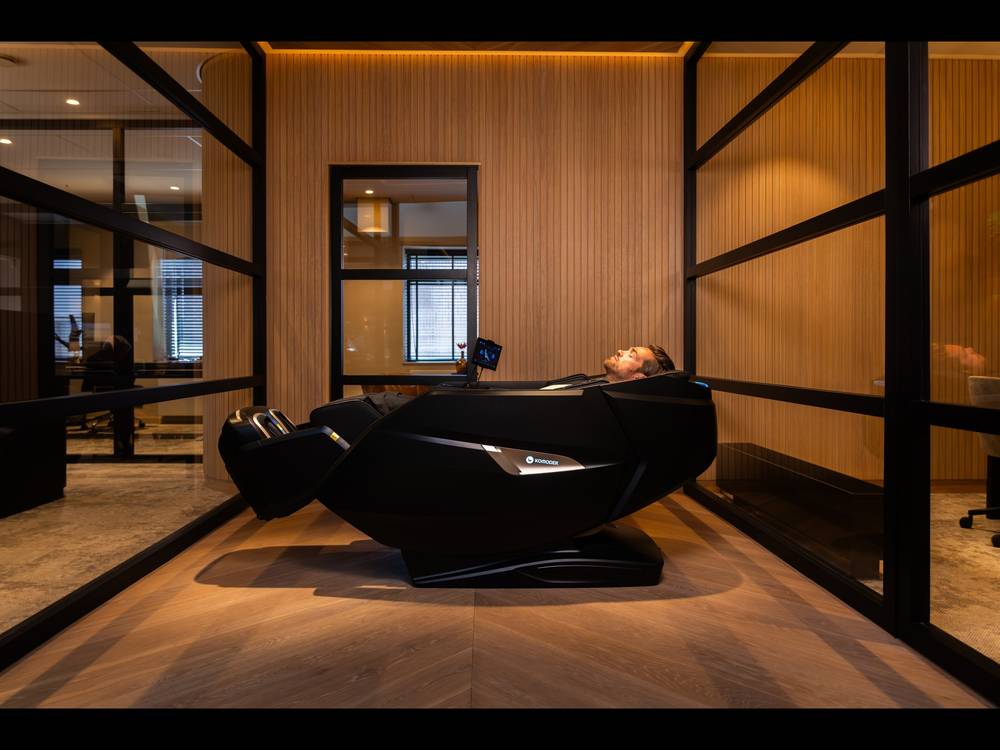 Massagesessel in einer eingerichteten Lounge mit Holz und warmem Licht